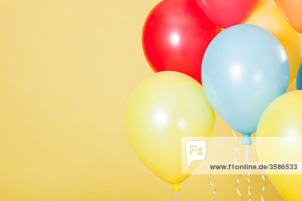 Bunte Partyballons vor gelbem Hintergrund