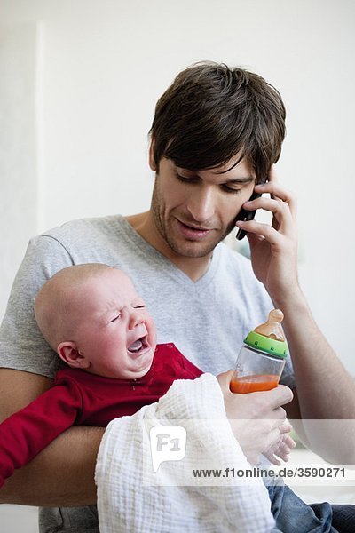 Mann mit Baby beim Telefonieren
