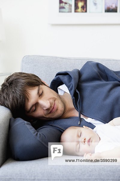 Vater und Baby schlafen auf der Couch