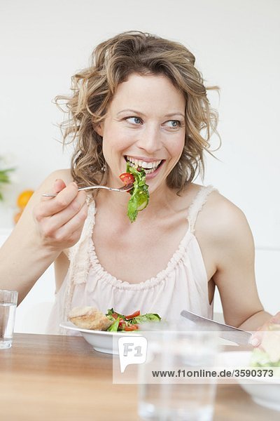 Woman eating mixed salad on table