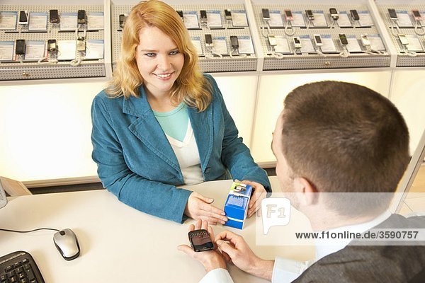 Mitarbeiter  der einem Kunden ein Handy zeigt