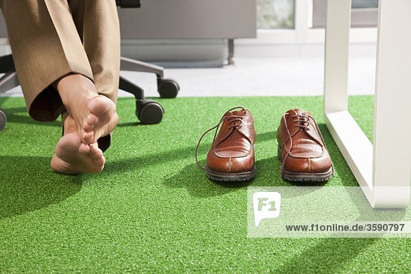 Entspannte Füße auf einem grünen Büroteppich