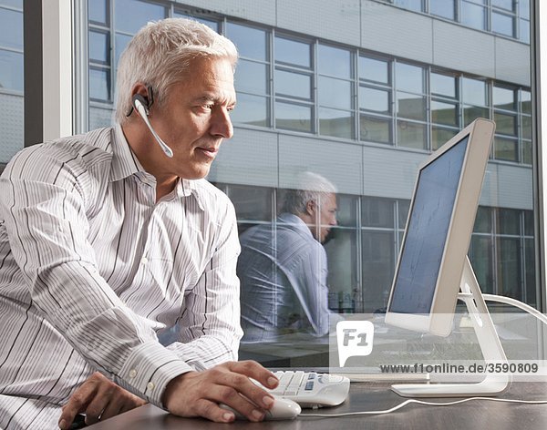 Mann mit Headset arbeitet am Computer