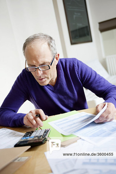 Man using calculator and filling his tax form