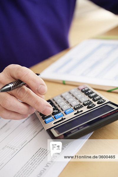 Man using calculator and filling his tax form