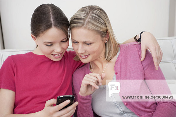 Woman and her daughter reading a text message on a mobile phone