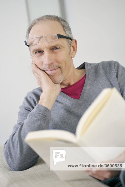 Porträt eines Mannes  der ein Buch hält und lächelt
