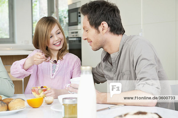 Mann beim Frühstücken mit seiner Tochter