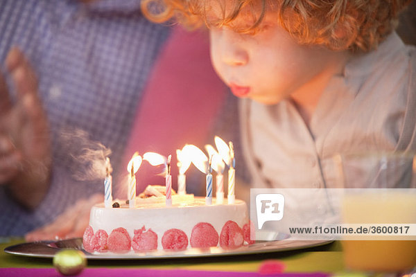 Boy blowing out candles on his birthday cake