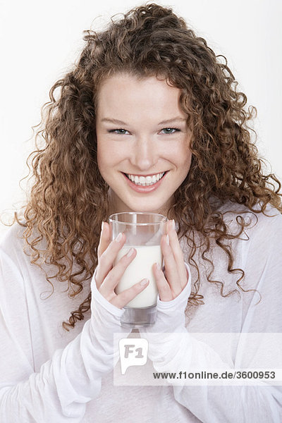 Porträt einer Frau  die ein Glas Milch hält und lächelt