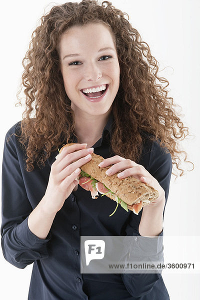 Eine Frau hält ein Sandwich und lacht.