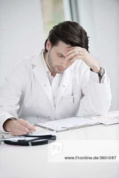Male doctor examining a medical report and looking upset