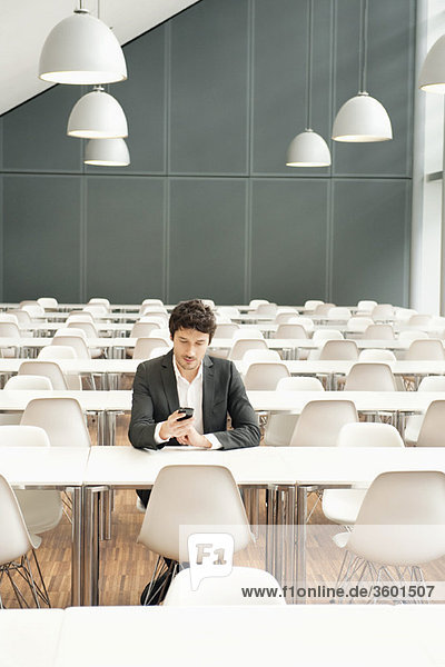 Businessman sitting at a cafeteria and using a mobile phone