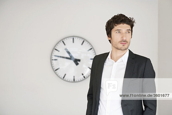 Businessman standing in front of a clock