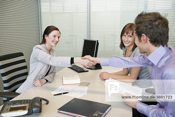 Female real estate agent shaking hands with a couple