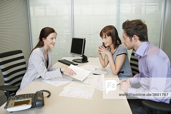 Female real estate agent showing a brochure to a couple