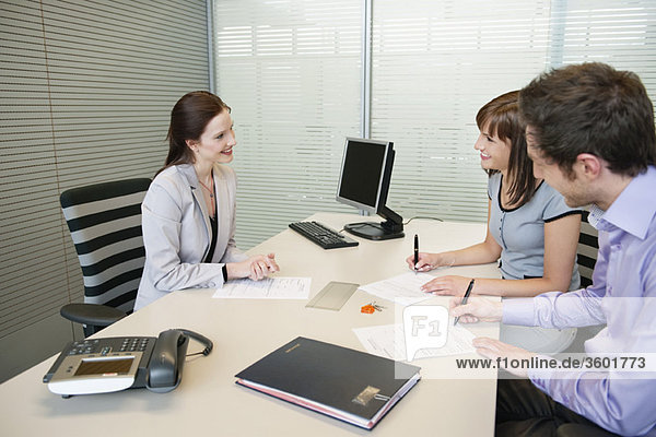 Couple signing agreement form in a real estate agent's office