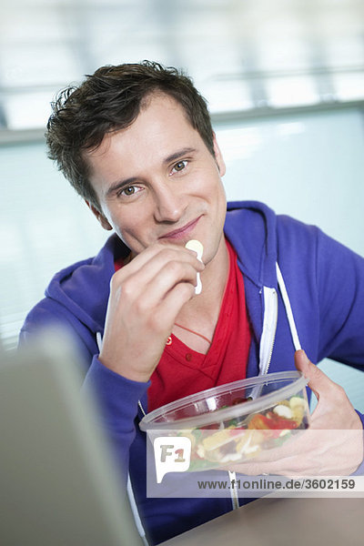 Geschäftsmann beim Essen von Kaugummidrops vor einem Laptop