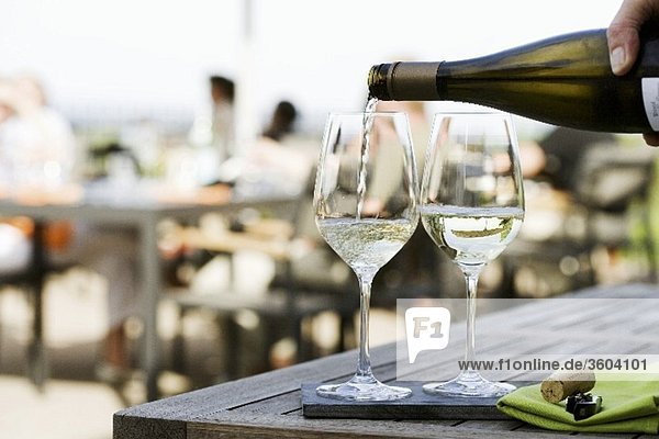Weisswein auf der Terrasse eines Restaurants einschenken
