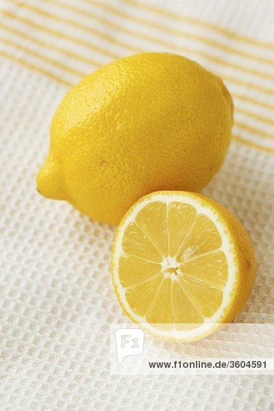 Ganze und halbe Zitrone auf Geschirrtuch
