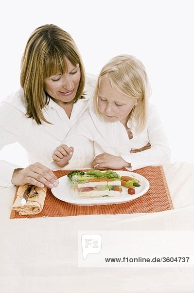 Mutter und Tochter sitzen am Tisch vor Gemüseterrine