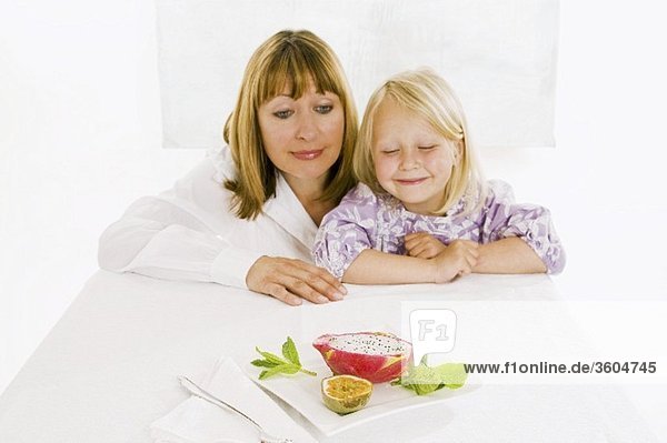 Mutter und Tochter sitzen am Tisch vor Obstteller
