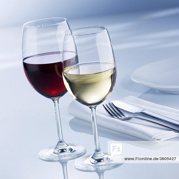 Weissweinglas und Rotweinglas neben Gedeck