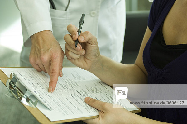 Arzt hilft dem Patienten beim Ausfüllen der medizinischen Unterlagen
