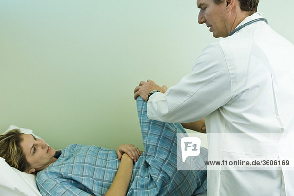 Doctor examining patient's leg and knee joint flexibility
