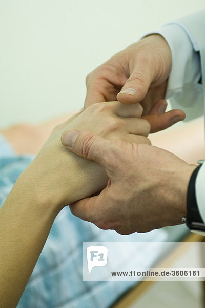 Doctor examining patient's fingers