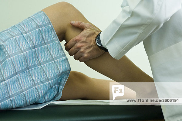 Doctor examining patient's leg and knee