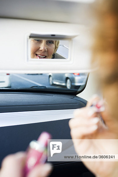 Frau im Auto beim Schminken mit Visier-Eitelkeitsspiegel