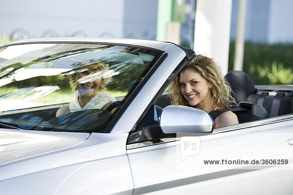 Young woman driving convertible with friend