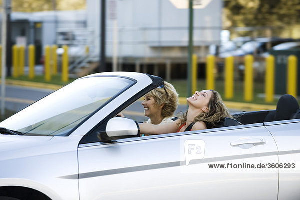 Young woman driving convertible  enjoying outing with mother