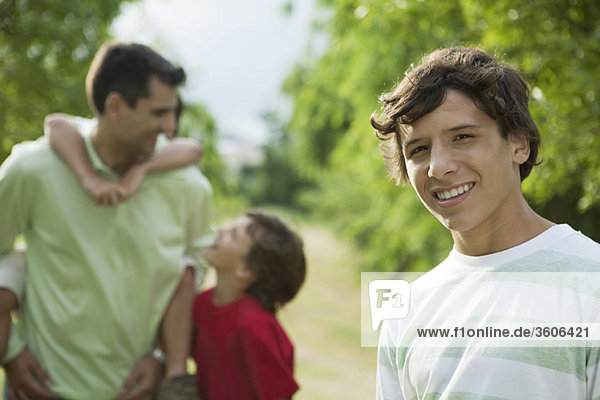 Teenage boy outdoors with father and younger brothers  portrait