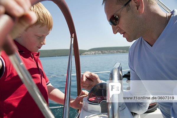 Man explaining boy compass on yacht