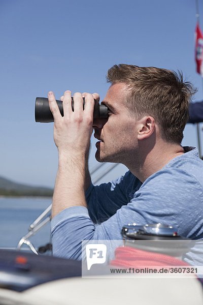 Mann mit Fernglas auf der Yacht