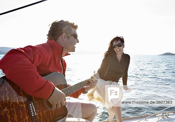 Frau und Mann spielen Gitarre auf der Yacht