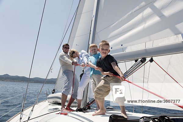 Family pulling rope on yacht