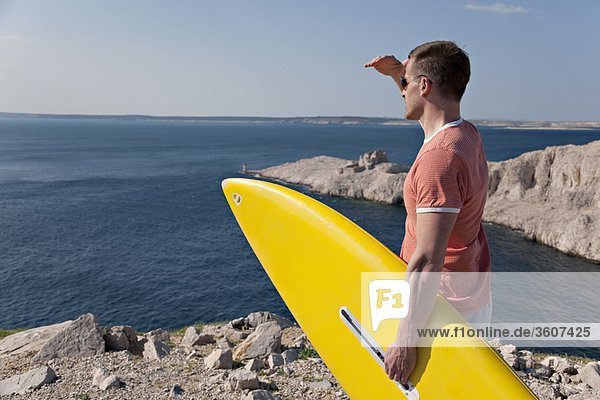Man with surfboard looking at sea