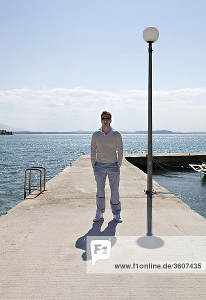 Man standing on pier by sea