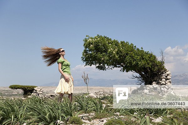 Woman with windblown hair and tree