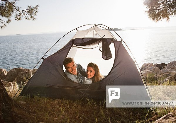 Couple lying in tent by sea