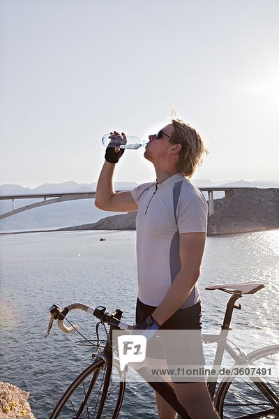 Cyclist drinking water by sea