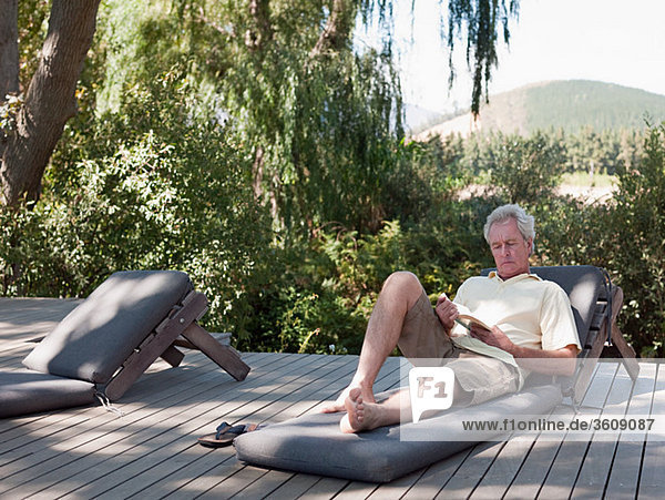 Senior man reading on sun lounger