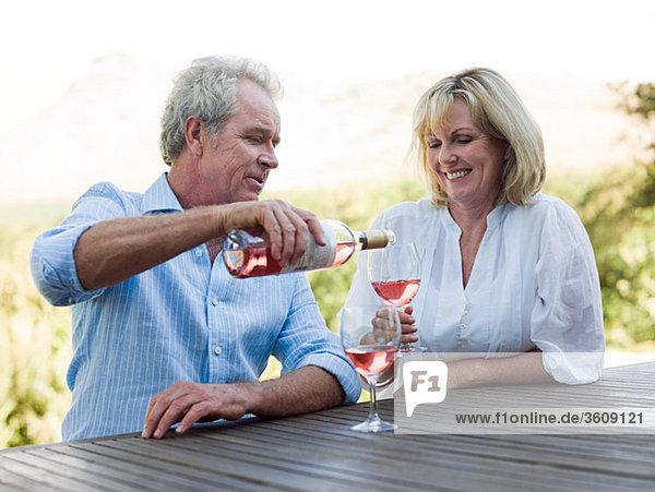 Man pouring wine for woman