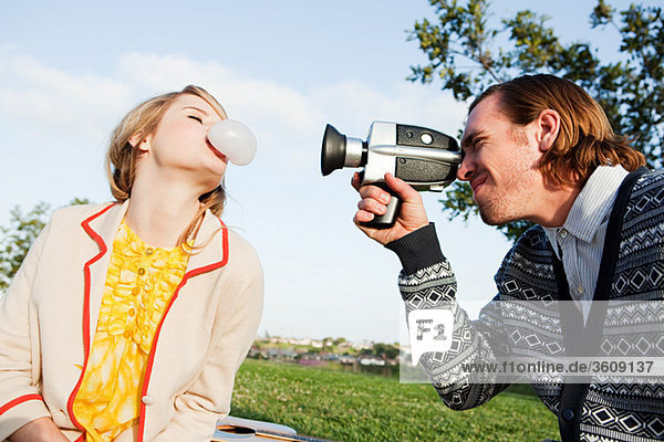 Man filming girlfriend blowing bubble gum
