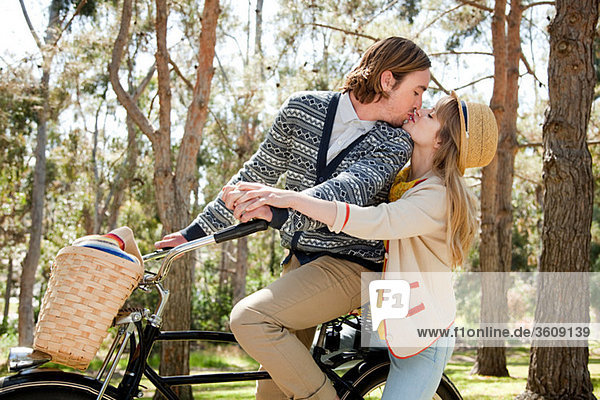 Young couple kissing on bicycle