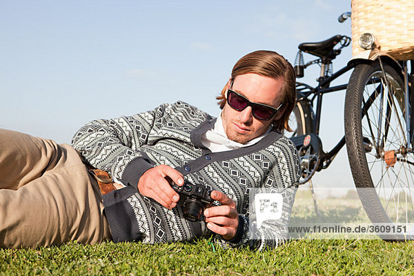 Young man in field with camera and bicycle