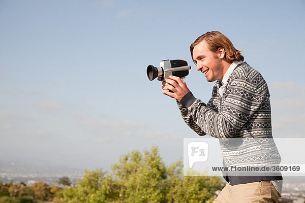 Young man using video camera outdoors
